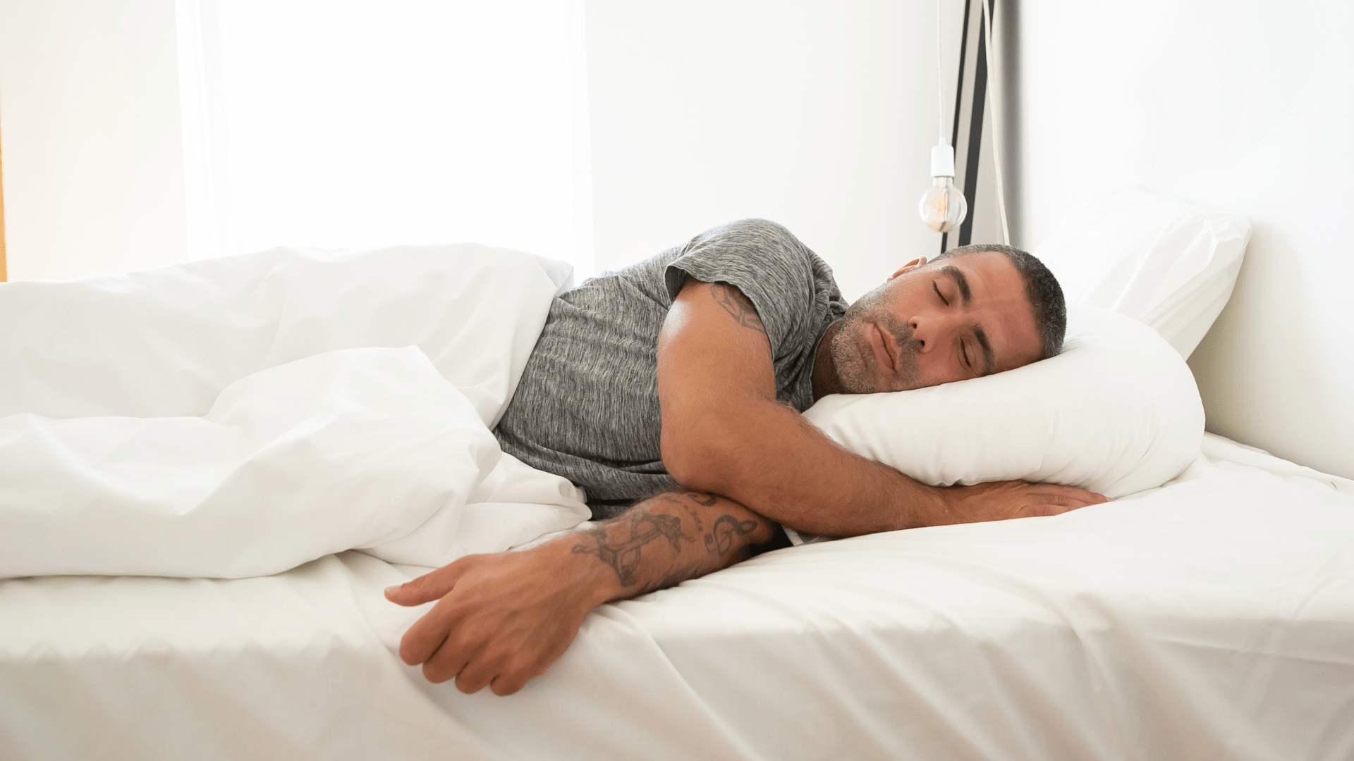 A middle aged man sleeping in bed.